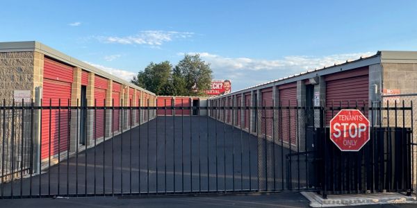 Rows of red roll-up storage units behind a secure gate at Gold Star Self Storage